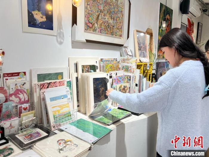 圖為藝術(shù)品商店內(nèi)，顧客挑選插畫作品?！＄婌?攝