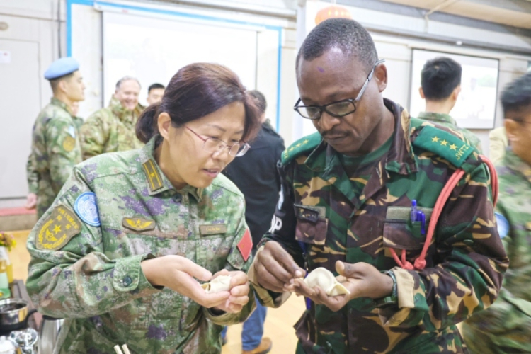 圖為維和官兵與外軍人員共同包餃子。胡光明攝