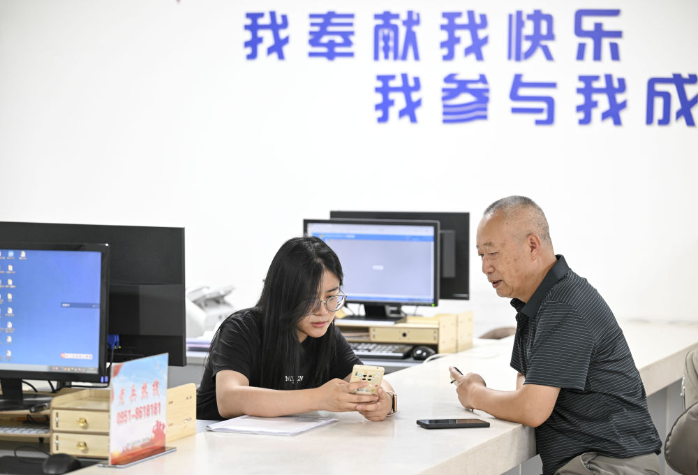 2024年6月20日，在寧夏銀川市金鳳區(qū)長城花園社區(qū)黨群服務中心，工作人員幫助居民辦理業(yè)務。圖片來源 新華社