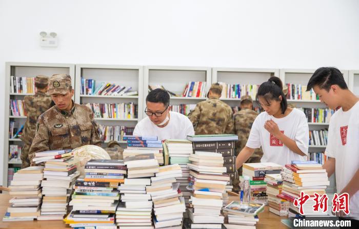 圖為志愿者們和邊防戰(zhàn)士整理圖書。　劉曉東 攝