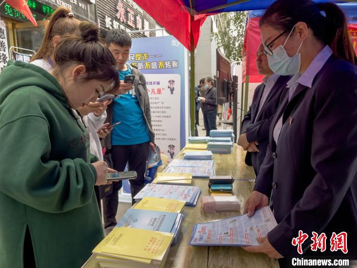 圖為工作人員正在向路過市民介紹國家反詐中心軟件的功能?！≈x牧 攝